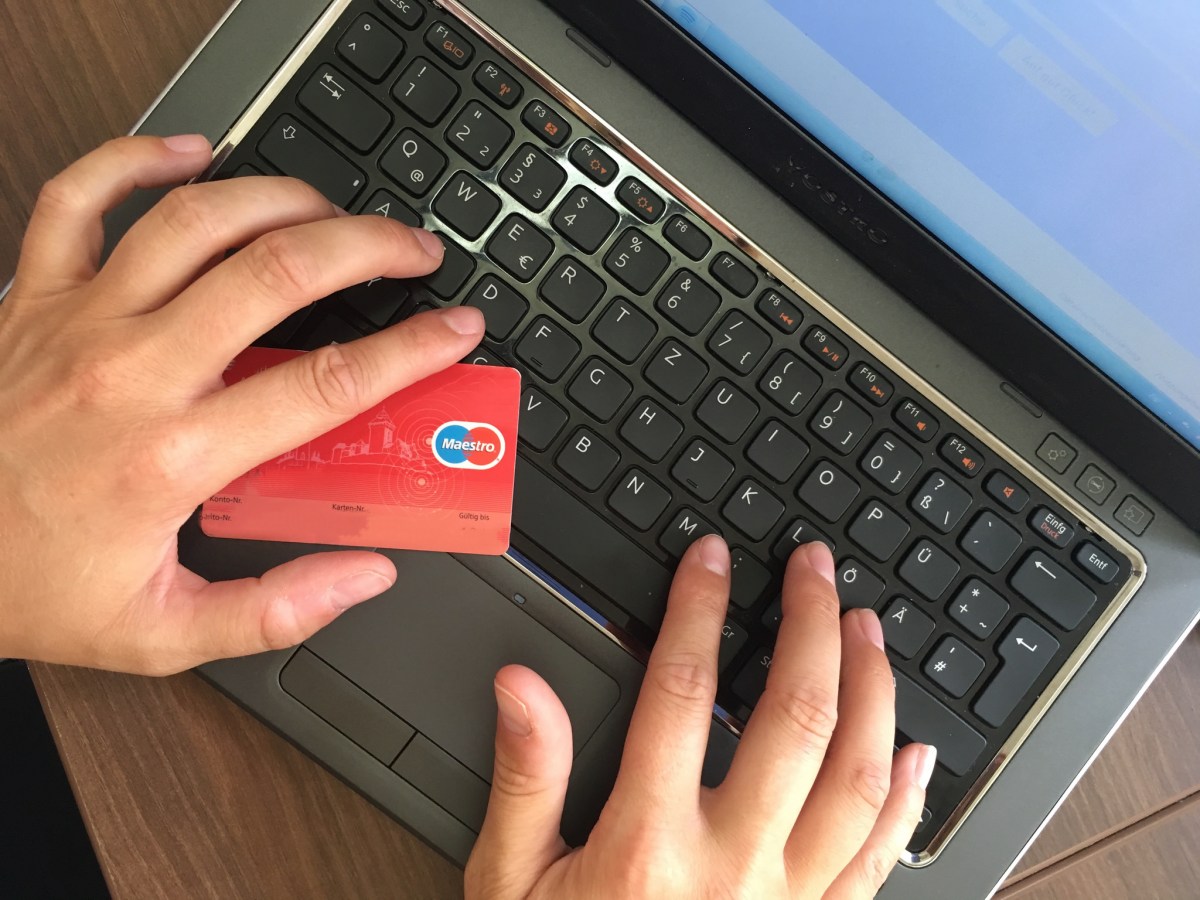 person holding credit card while using laptop